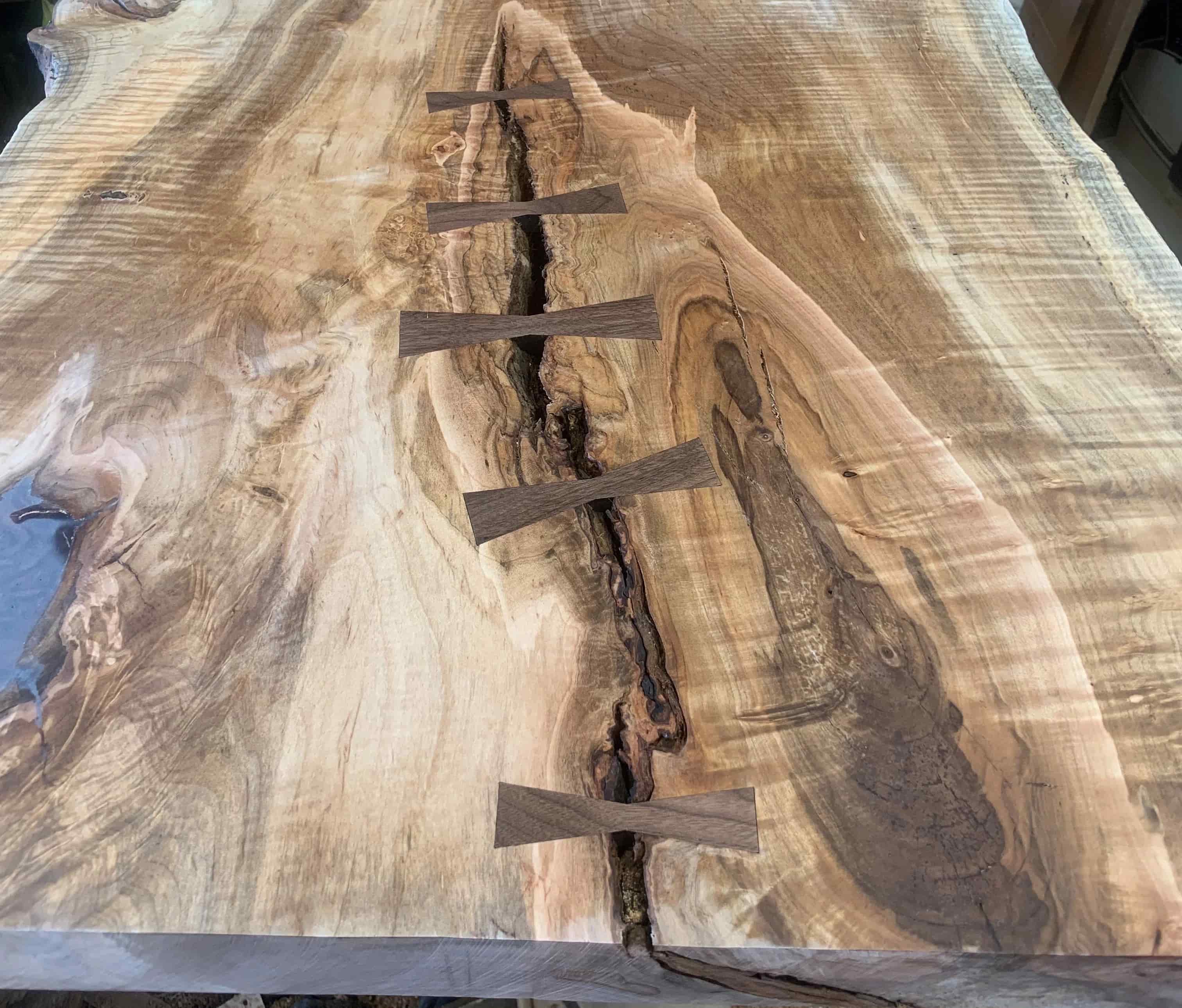 A close up of Slab Stitcher wooden slimline inlays laying on a piece of wood.